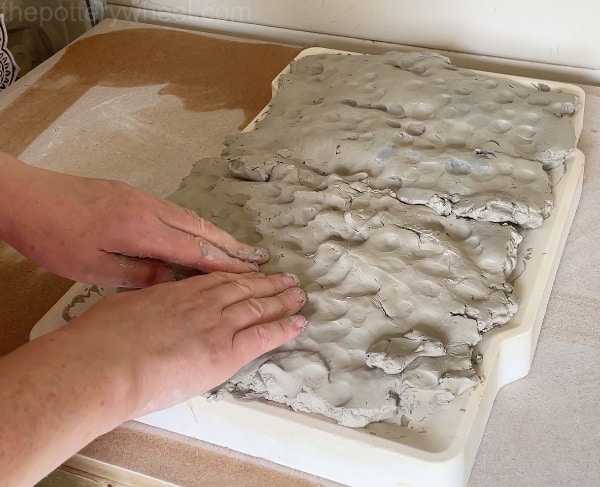 Pressing clay against the plaster slab