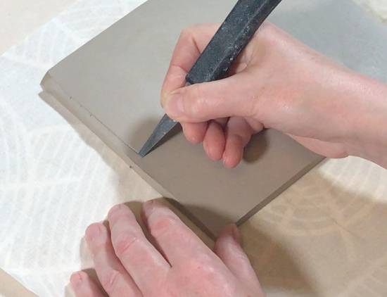 cutting a beveled edge in clay with a knife