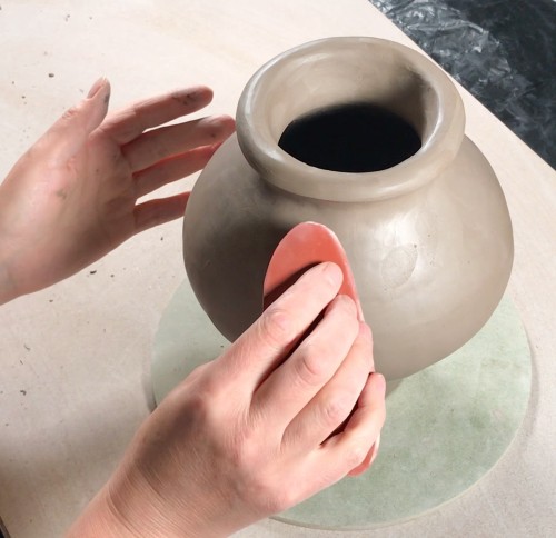 Smoothing the pottery surface with rubber rib tool