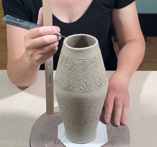 Trimming the top edge of clay vase