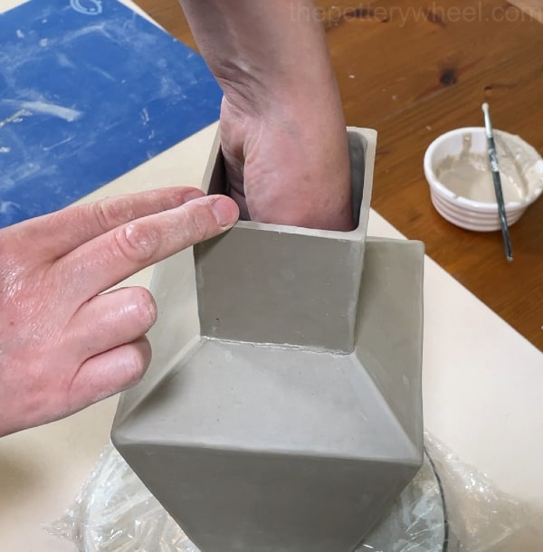 fixing the neck on the clay vase
