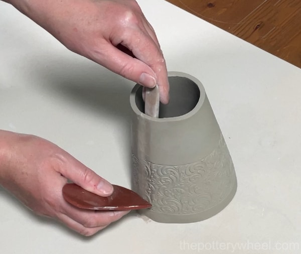 smoothing the seam of the clay vase