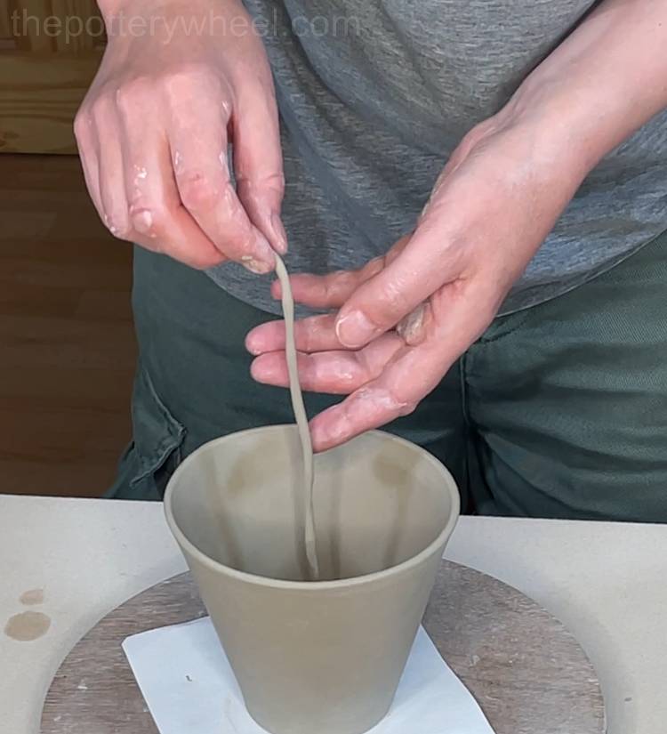 putting a clay coil in the base of the mug