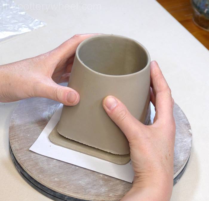 lowering the square bottomed slab mug onto the base