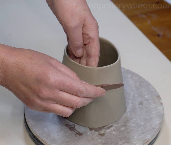 smoothing the square bottomed slab mug with a rubber rib
