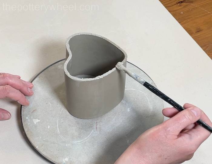 applying slip to the bottom of the heart shaped slab mug
