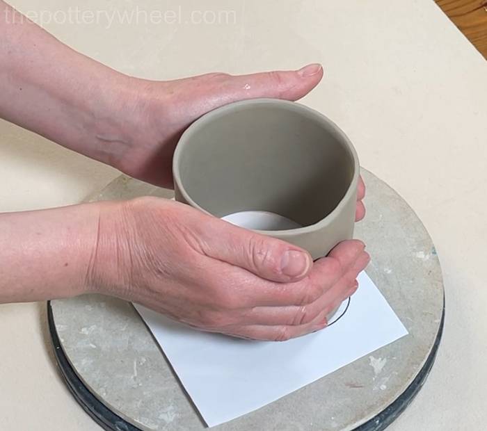 moving the clay cylinder onto the template for the heart shaped slab mug