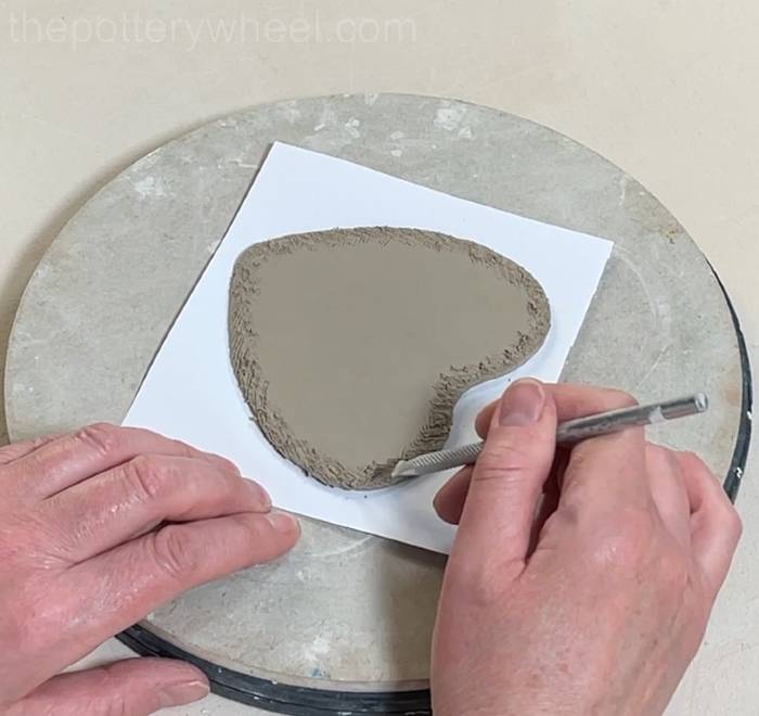 scoring the base of the heart shaped slab pottery mug