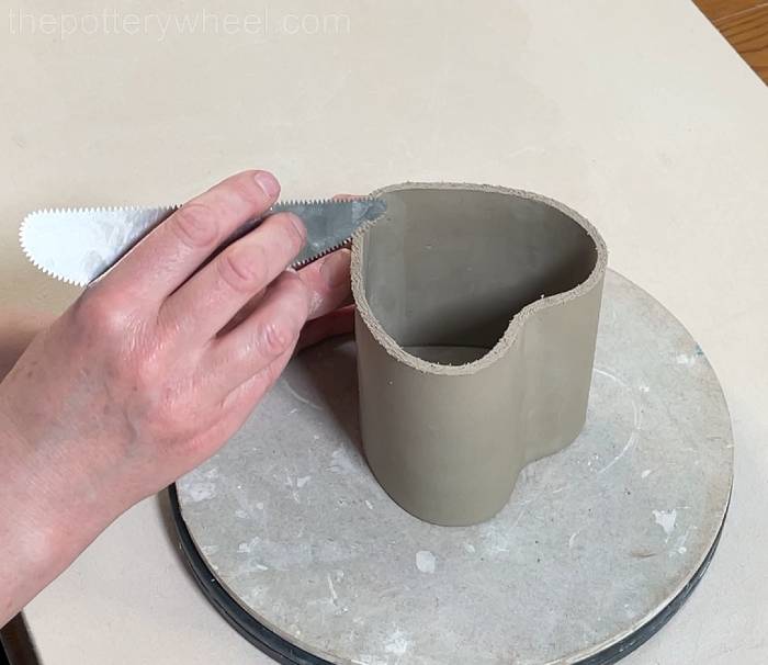 scoring the bottom edge of the heart shaped slab pottery mug