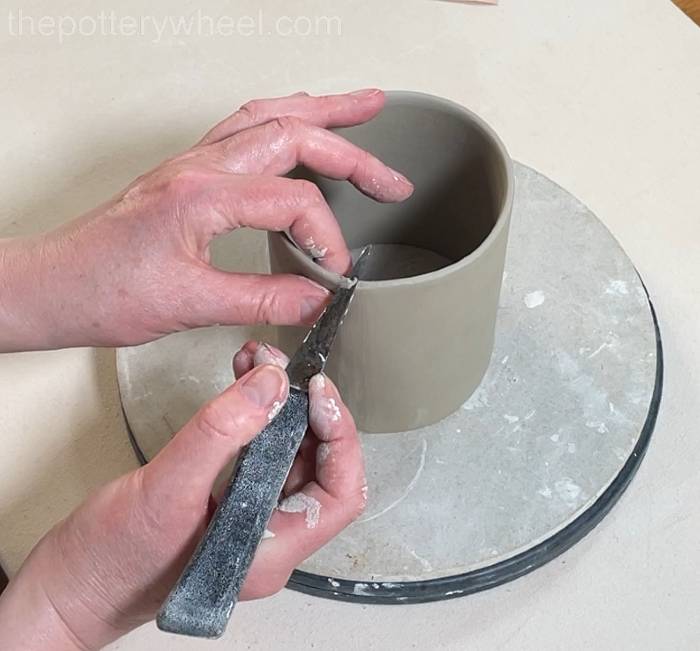 tidying up the edge of the heart shaped slab pottery mug