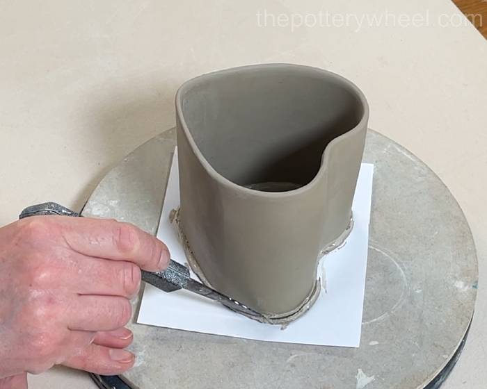 trimming the excess clay off the base of the mug