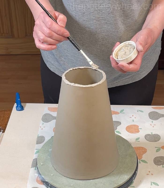 applying slip to the top edge of the flower jug vase