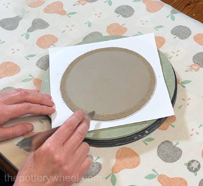 scoring the edge of the base of the flower jug vase