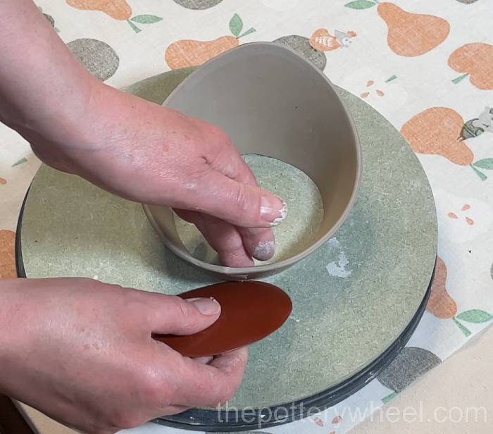 smoothing the outside surface of the flower jug vase rim