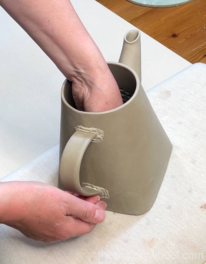 Pressing the handle onto the square-based teapot